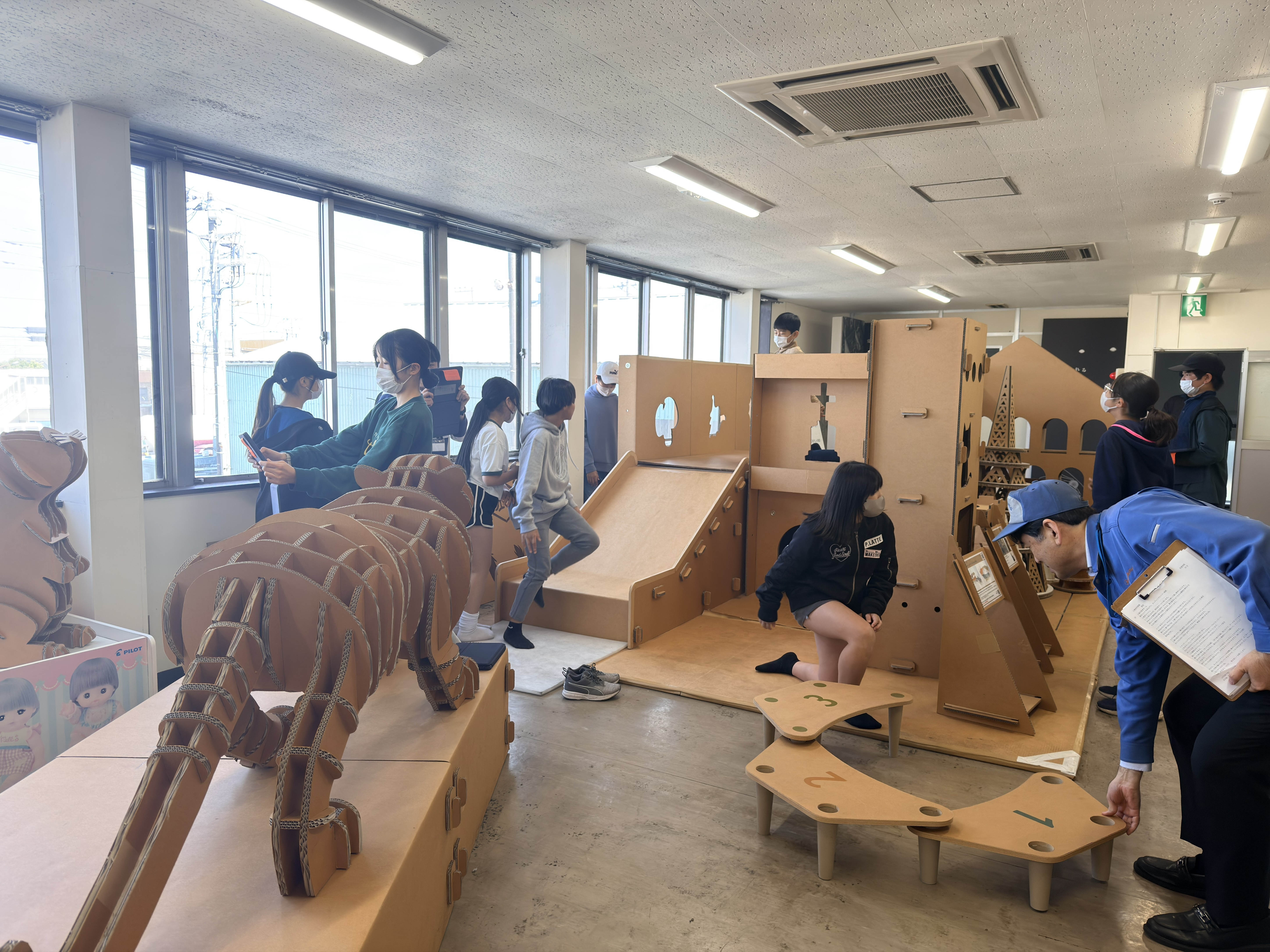 強化ダンボール製のすべり台で遊ぶ児童